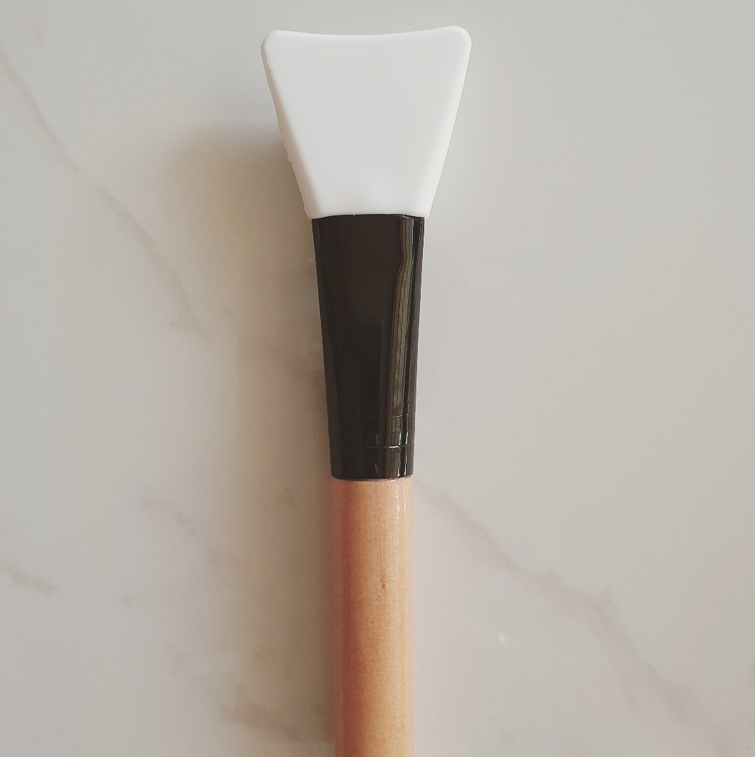 Silicone flat tip face mask applicator with wooden handle.